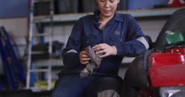 Kadın tamircinin portresi, araba servis istasyonunda oturan bir bezle ellerini temizliyor. otomobil tamir servisi