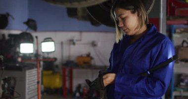 Araba servis istasyonunda elinde lamba tutan koruyucu eldiven takan kadın tamirci. otomobil tamir servisi