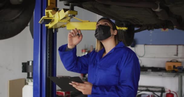Kobieta Mechanik Masce Robi Notatki Pod Samochodem Stacji Benzynowej Serwis — Wideo stockowe