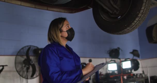 Mecânico Feminino Usando Máscara Facial Segurando Prancheta Inspecionando Carro Uma — Vídeo de Stock