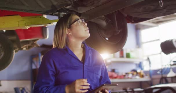 Mecánica Femenina Usando Tableta Digital Pie Debajo Coche Una Estación — Vídeo de stock