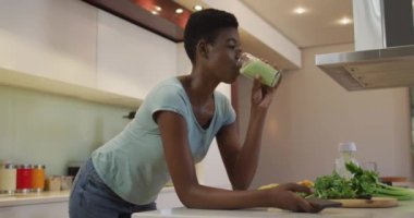 Gülümseyen Afro-Amerikan çekici kadın mutfakta ev yapımı smoothie içiyor. evde sağlıklı beslenme ve yaşam tarzı.