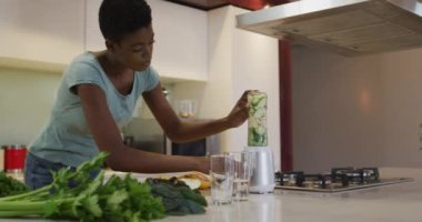 Afro-Amerikan çekici kadın mutfakta smoothie için malzemeleri karıştırıyor. evde sağlıklı beslenme ve yaşam tarzı.