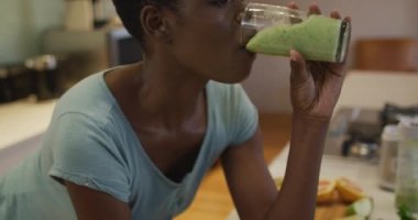 Gülümseyen Afro-Amerikan çekici kadının portresi. Mutfakta ev yapımı smoothie içiyor. evde sağlıklı beslenme ve yaşam tarzı.