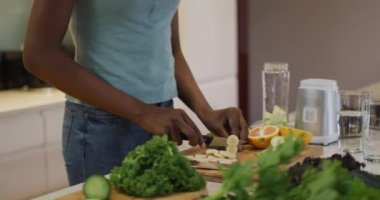 Afro-Amerikan çekici kadın mutfakta meyve püresi için sebze doğruyor. evde sağlıklı beslenme ve yaşam tarzı.