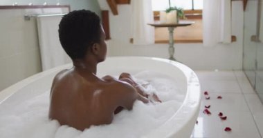 Afro-Amerikan çekici bir kadının banyoda köpük banyosunda rahatladığını gördüm. güzellik, şımartma, spa ve refah konsepti.