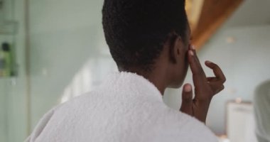 Afro-amerikan çekici kadın banyoda yüz bakımı yapıyor. güzellik, şımartma, spa ve refah konsepti.