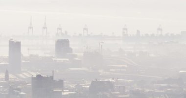 Şehir manzarası, birden fazla bina ve sisle kaplı tersane. Skyline ve modern endüstriyel şehir mimarisi.
