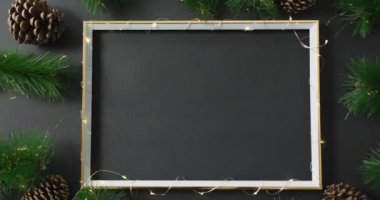 Çerçeve etrafında dizgi ışıkları olan ve siyah arkaplanda boşluğu kopyalayan yılbaşı dekorasyonlarının videosu. Noel, gelenek ve kutlama konsepti.