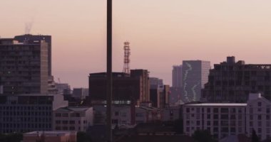 Gün batımında birden fazla uzun gökdelen ve bina olan şehir manzarası. Skyline ve modern şehir mimarisi.