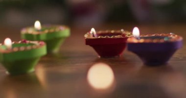 Tahta masadaki dekoratif kil kaplarda dört mum, ön planda bokeh alevi. diwali festivali, kutlama, gelenek ve tören konsepti.