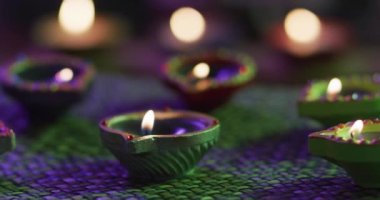 Dekoratif kil kaplarda mumlar örülmüş masa örtüsünde, ön planda odaklanmış, arka planda bokeh. diwali festivali, kutlama, gelenek ve tören konsepti.