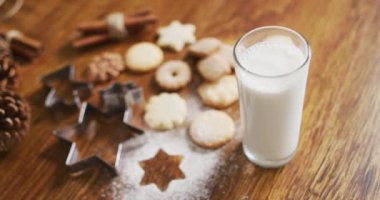 Ahşap zemin üzerinde bir bardak süt ve kurabiye olan Noel süslerinin videosu. Noel, gelenek ve kutlama konsepti.