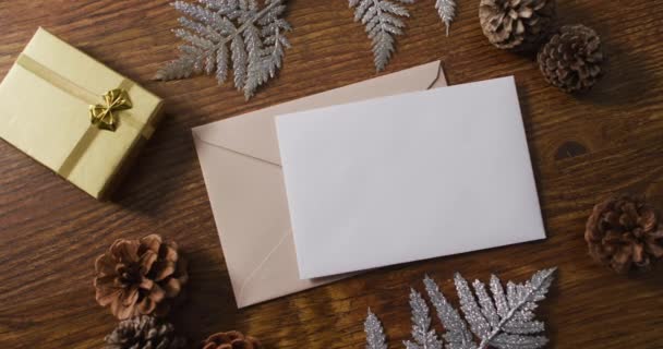 Video Van Kerstversiering Met Witte Kaart Beige Envelop Houten Achtergrond — Stockvideo