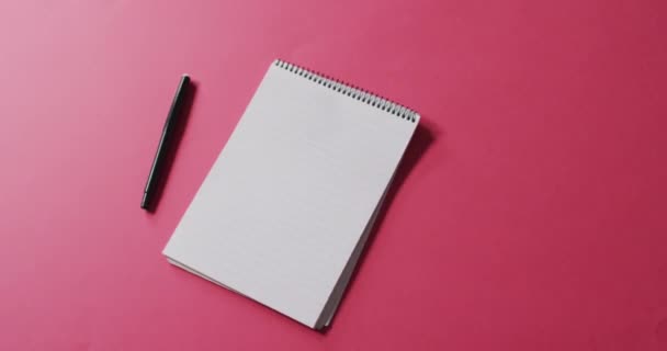 ピンクの背景にコピースペースのあるペンとノートブックのビデオ コミュニケーションと伝統の概念は — ストック動画