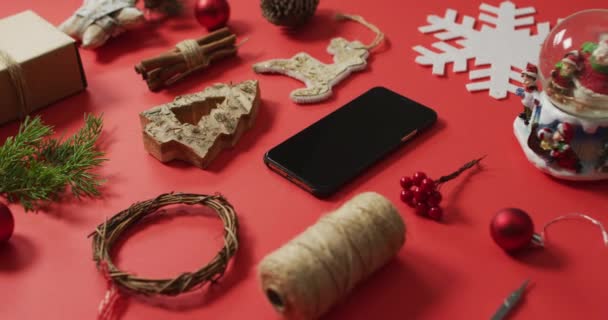 圣诞装饰品和树的分支的视频 带有红色背景的智能手机 圣诞节 传统和庆祝概念 — 图库视频影像