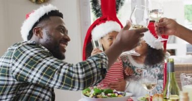 Mutlu Afro-Amerikan ailesi Noel Baba şapkası takıp mutfakta kutluyor. Aile Noel 'i ve şenliği evde birlikte kutluyoruz..