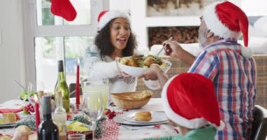 Mutlu Afro-Amerikan ailesi Noel Baba şapkası takıp mutfakta kutlama yapıyor. Aile Noel 'i ve şenliği evde birlikte kutluyoruz..