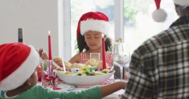 Mutlu Afro-Amerikan ailesi Noel Baba şapkası takıp mutfakta kutlama yapıyor. Aile Noel 'i ve şenliği evde birlikte kutluyoruz..