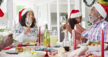 Mutlu Afro-Amerikan ailesi Noel Baba şapkası takıp bayram yemeğini kutluyor. Aile Noel 'i ve şenliği evde birlikte kutluyoruz..
