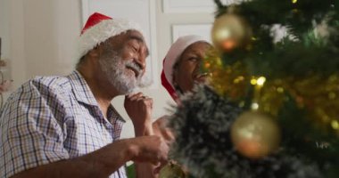 Mutlu Afro-Amerikan son sınıf çifti yılbaşı ağacını birlikte süslüyor. Noel, şenlik ve evde gelenek.