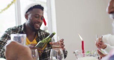 Mutlu Afrikalı Amerikalı kadın Noel Baba şapkası takıp yemeği kutluyor. Aile Noel 'i ve şenliği evde birlikte kutluyoruz..