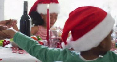 Mutlu Afro-Amerikan ailesi Noel Baba şapkası takıp mutfakta kutlama yapıyor. Aile Noel 'i ve şenliği evde birlikte kutluyoruz..