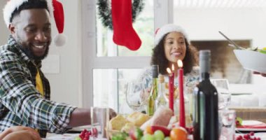 Mutlu Afro-Amerikan ailesi Noel Baba şapkası takıp mutfakta kutlama yapıyor. Aile Noel 'i ve şenliği evde birlikte kutluyoruz..