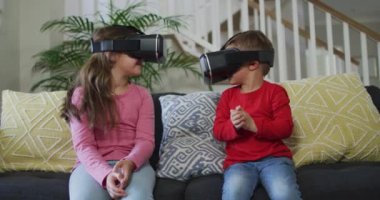 Kafkasyalı kardeşlerin kulaklık takması, kanepeye oturması ve eğlenmesi. çocukluk, eğlence ve keşif teknolojiyi evde kullanmak.