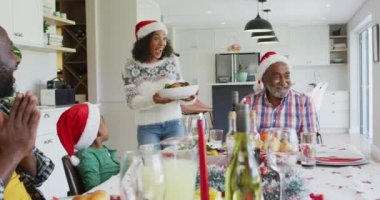 Mutlu Afro-Amerikan ailesi Noel Baba şapkası takıp mutfakta kutlama yapıyor. Aile Noel 'i ve şenliği evde birlikte kutluyoruz..