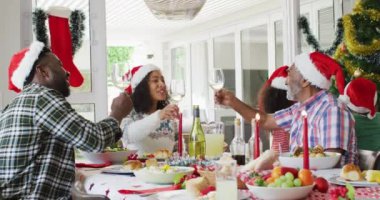 Mutlu Afro-Amerikan ailesi Noel Baba şapkası takıp bayram yemeğini kutluyor. Aile Noel 'i ve şenliği evde birlikte kutluyoruz..