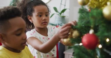 Mutlu Afro-Amerikan kardeşler Noel ağacı süslüyorlar. Aile Noel 'i ve şenliği evde birlikte kutluyoruz..