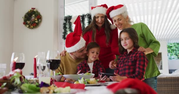 Glückliche Kaukasische Mehrgenerationenfamilie Mit Weihnachtsmützen Die Aufs Smartphone Schauen Familienweihnachtszeit — Stockvideo