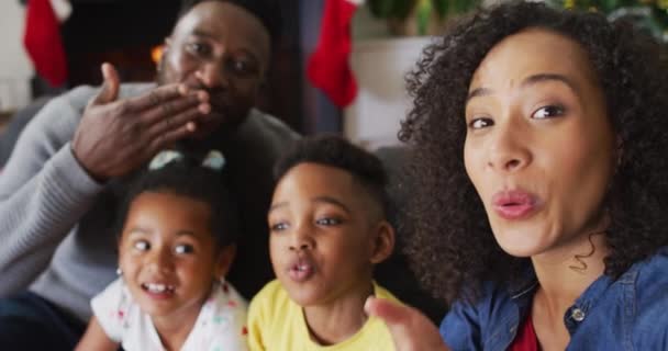 アフリカ系アメリカ人の家族の笑顔ビデオ通話でキスを送信 背景にクリスマスの装飾 クリスマスの時間と祭りを一緒に家で — ストック動画