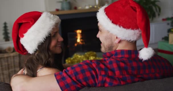 Achteraanzicht Van Gelukkig Kaukasisch Echtpaar Met Kerstmutsen Bank Kerstmis Festiviteit — Stockvideo