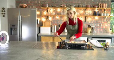 Mutfakta beyaz bir kadın elinde kaseyle hamurun üzerine serpiştirip, tel soğutma rafına kaldırıyor. Fırın, aşçılık, kırsal, sağlıklı, yerli, esnaf, yemek hazırlama