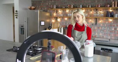 Beyaz kadın un kavanozunu kapıyor, kâseye karışıyor ve mutfak adasında hamuru hazırlamak için çırpıyor. Pişirme, aşçılık, yerli, minimalist, canlı, yaşam tarzı, yemek hazırlama