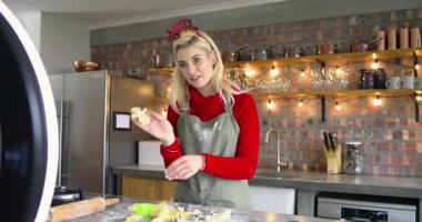 Özel ders için mutfak adasında çerez kesen hafif telefon rehberi kadın. Pişirme, tatil, şenlik, aşçılık, öğretici, modern, samimi