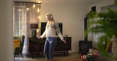 Müzik kulaklık takan, dans eden, akıllı telefona basan, oturma odasında arama yapan bir kadın. Yaşam tarzı, rahatlama, eğlence, modern, rahat, neşeli, aktivite