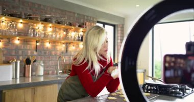 Kadın, kameraya talimat verirken mutfaktaki kurabiyelere krema tadı veriyor. Pişirme, işçilik, aşçılık, yaşam tarzı, kırsal, canlı, yaratıcılık