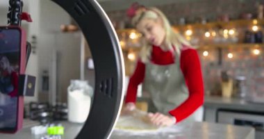 Yüzük çerçeveli telefon, mutfak dersi için hamur yoğurucu gösteren bir kadın olduğunu gösteriyor. Pişirme, pişirme, aşçılık, süreç, ürün, yaşam tarzı, tanıtım