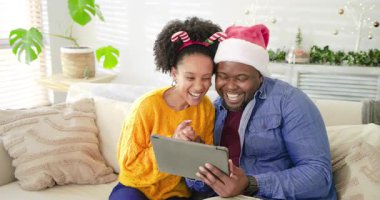 Tablette çeşitli çiftler birbirlerini selamlıyor, çelenk altında kanepede kucaklaşmadan önce el sallıyor ve gülüyorlar. Romantik, neşeli, rahat, neşeli, dijital, kutlama, samimi