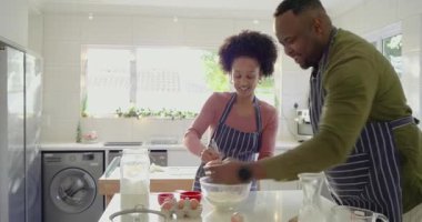Gülümseyen kadın ve Afrikalı Amerikalı adam mutfakta krep için hamuru çırpıyor ve yumurta kırıyor. Aşçılık, işbirliği, yerli, neşeli, aşçı, modern, sıcak