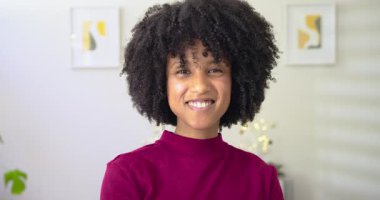 Kadın zumlayan kameraya tepki veriyor, gülümsüyor sonra oturma odasında izleyicileri parmak izleriyle selamlıyor. Portre, iç mekan, sıcaklık, mutluluk, zarafet, rahatlama, modern