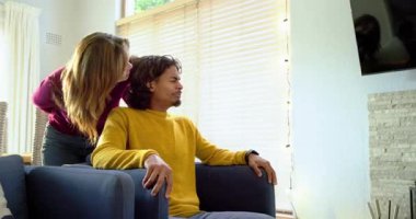 Hediye paketini açan çift, sıcak oturma odasındaki şömineye omuz omuza vuruyor, birlikte gülümsüyor. Sıcaklık, samimiyet, kutlama, rahatlama, rahatlık, arkadaşlık, köylülük