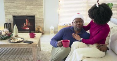 Kamera oyalanıyor, Noel Baba şapkalı ve boynuzlu çift ocakta kırmızı kupa yudumluyor, sıcaklığını paylaşıyor. Romantik, neşeli, samimi, sevecen, geleneksel, neşeli, mevsimsel