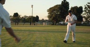 Koşu yapan erkek takım arkadaşları koltuk altında atış talimi yapıyor, kırmızı kriket topuyla sahaya çıkıyorlar. Sporcular, antrenman, açık hava, spor, takım çalışması, atletizm, yarışma