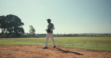 Sahaya erkek sporcu giriyor, toprağa basıyor, duruşunu değiştiriyor ve oynamak için eldiven kaldırıyor. Atletizm, spor, aktif, açık hava, rekabet, takım çalışması, fitness