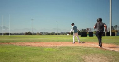 Koşucu, koşucu, koşucu, koşucu, hücum oyuncusu eldiven kaskıyla tümsekte sürtünen koşucuya tepki veriyor. Atletizm, spor, rekabet, açık hava, aksiyon, fitness, takım çalışması