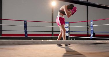 İniş yumruğu kadın boksörü dizlerinin üzerine çöktürüyor, koç bandı ringde ayarlıyor. Atletik, eğitim, savaş, kararlılık, esneklik, disiplin, takım çalışması